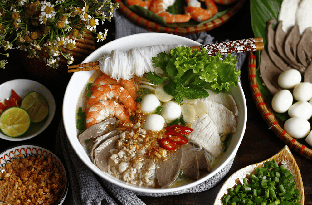 Clear noodle soup with fresh shrimp and herbs in ceramic bowl
